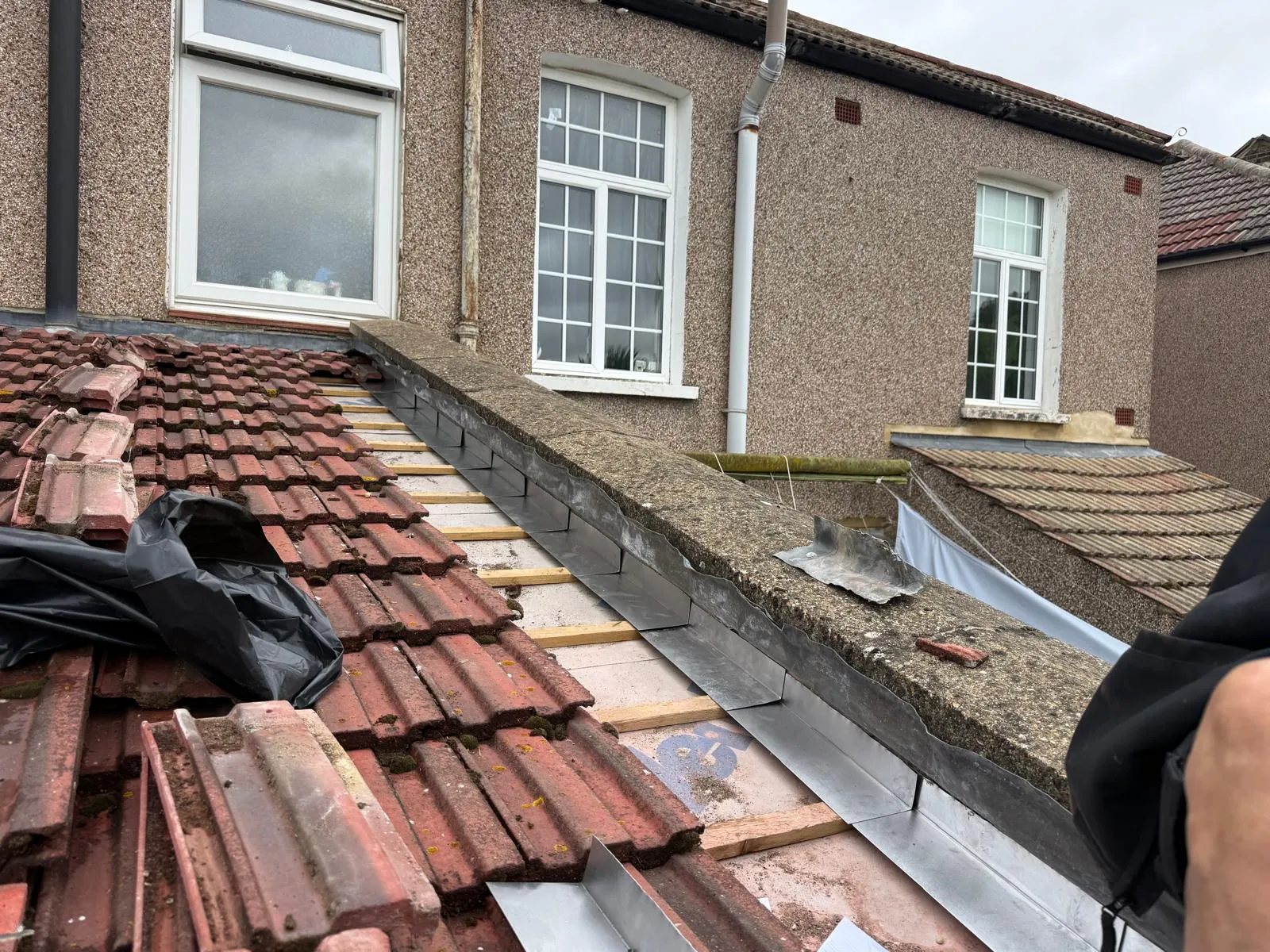 Old roof tiles stripped back with new lead flashing along the party wall