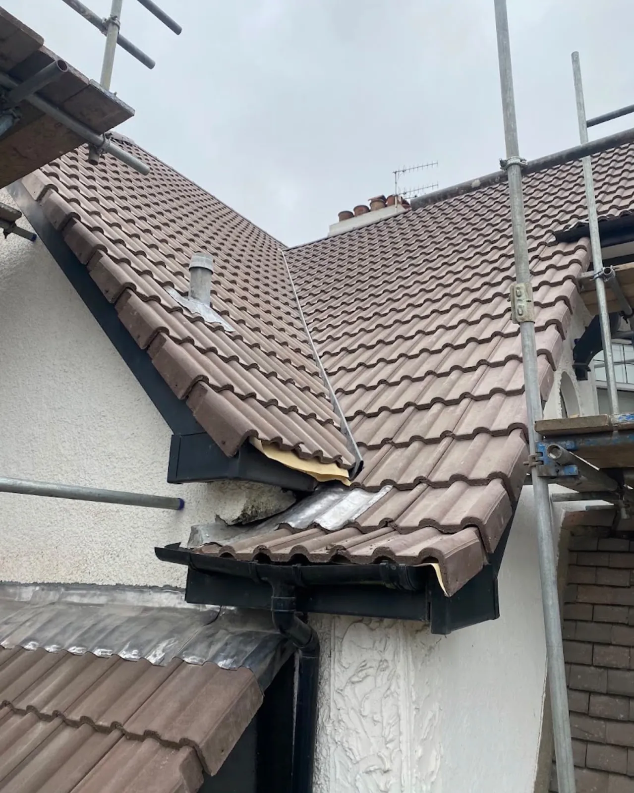Tiled roof valley with new black fascias and guttering