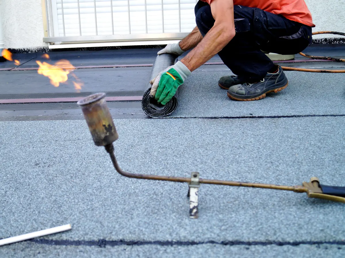 Roofer torch laying felt on a flat roof