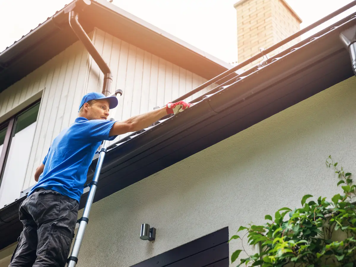 Clearing out a gutter from a ladder