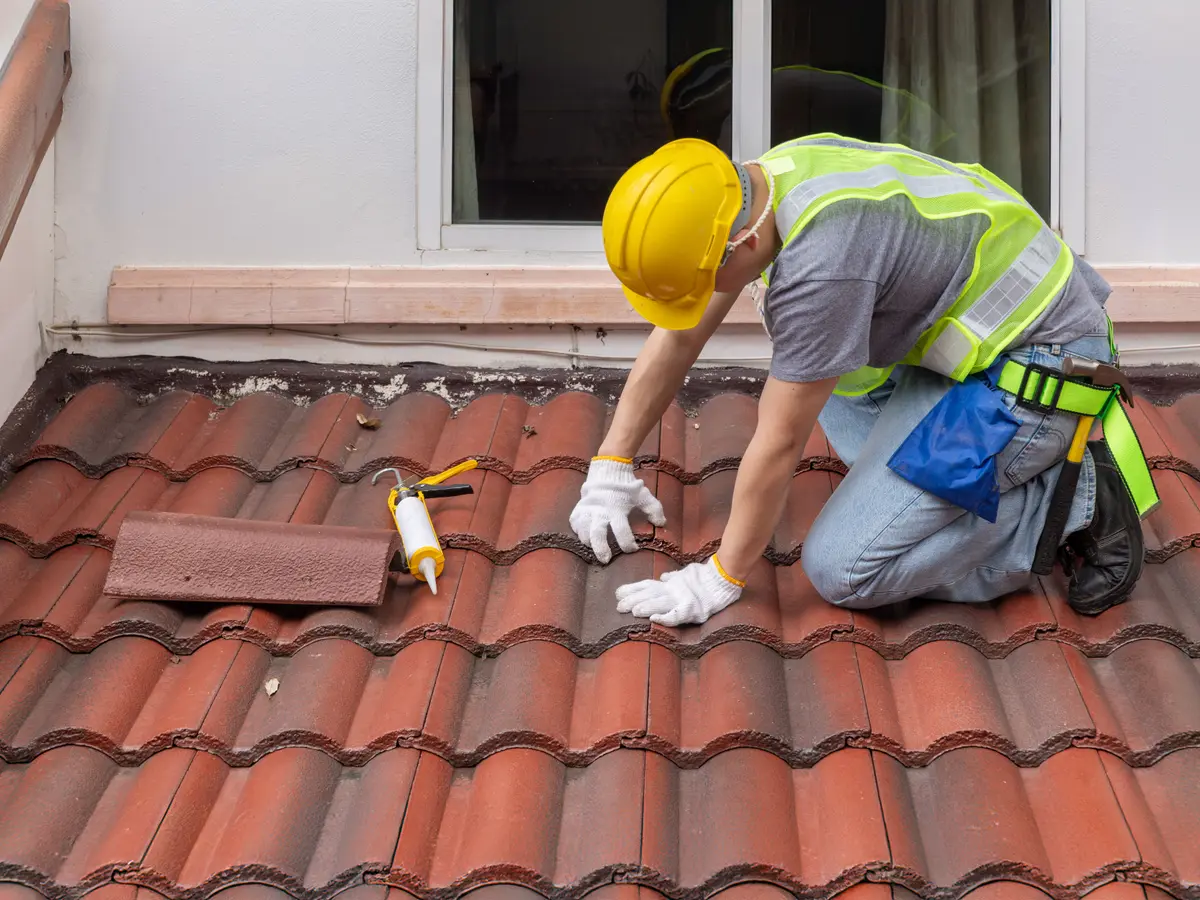 Roofer replacing a clay roof tile