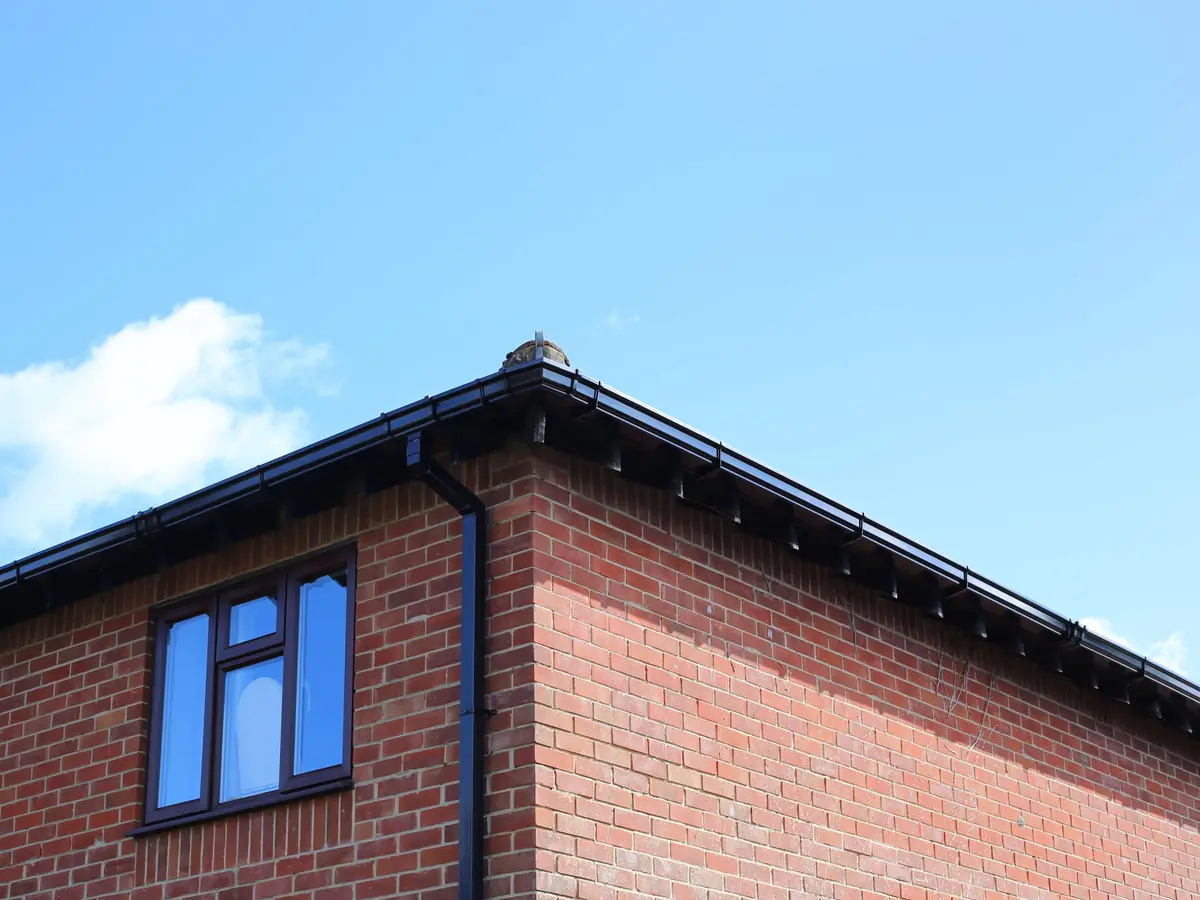 Black fascia, gutter and downpipe on a brick house
