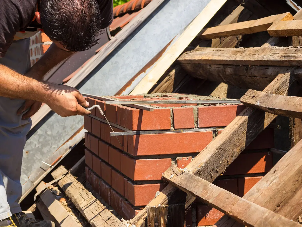 Bricklayer repairing a brick chimney stack