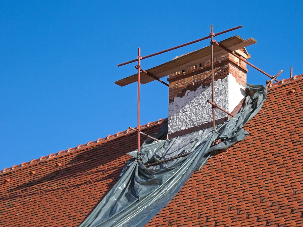 Temporary tarpaulin cover around a chimney on a tiled roof