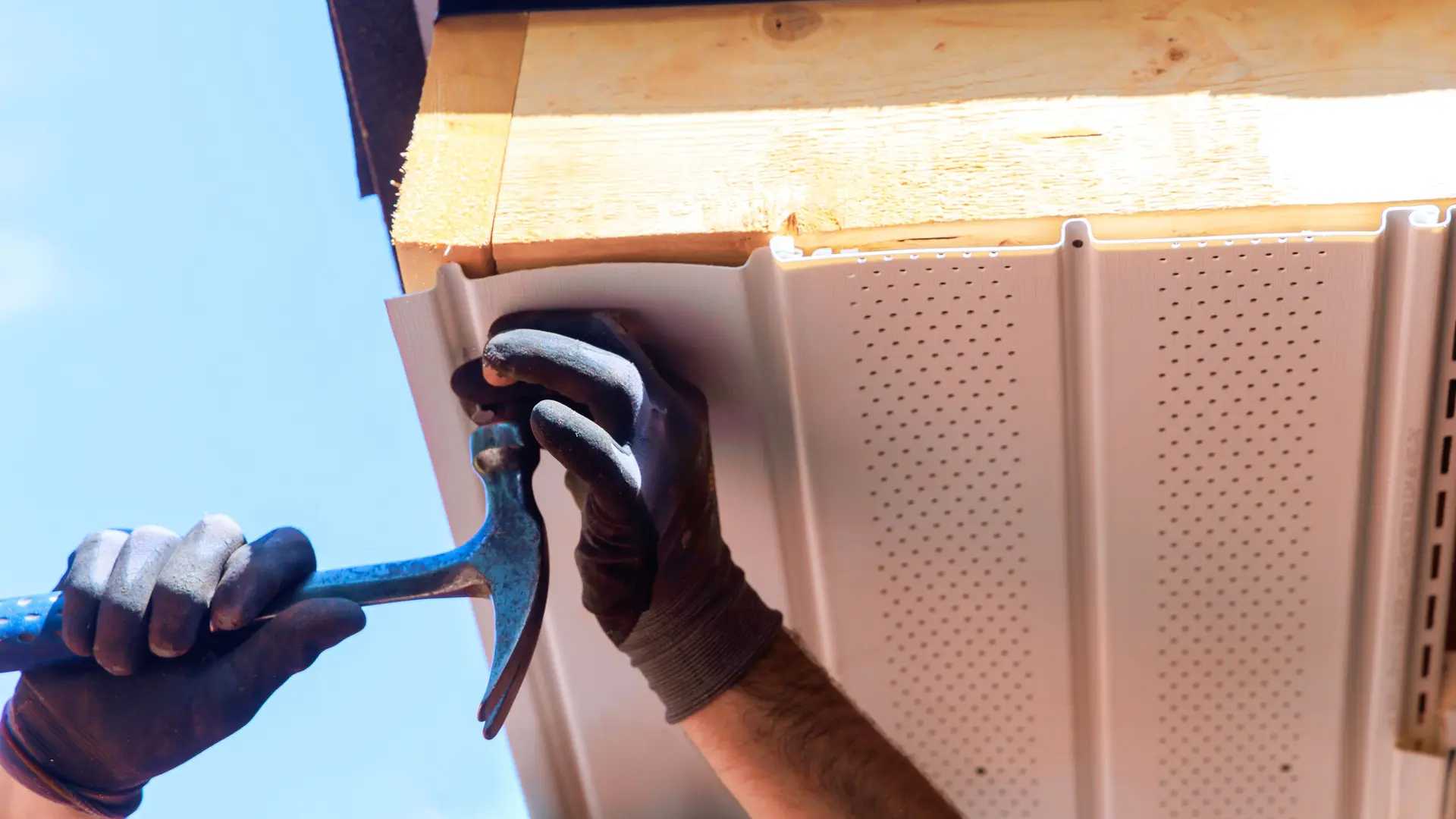 Roofer fitting a new vented soffit board