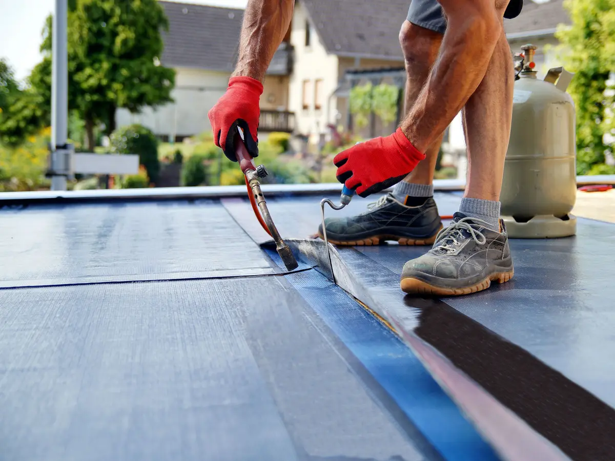 Roofer sealing a felt roof lap with a torch