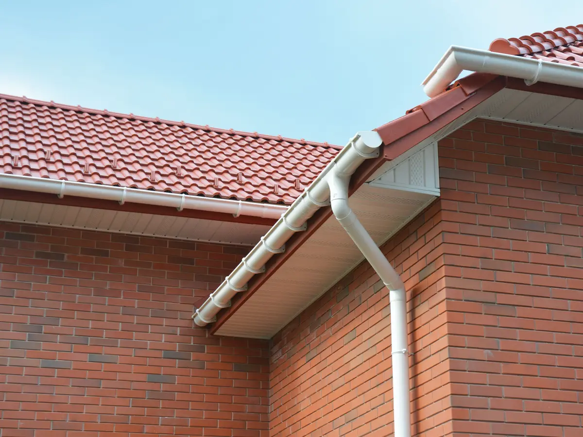 White gutter and downpipe on a brick house