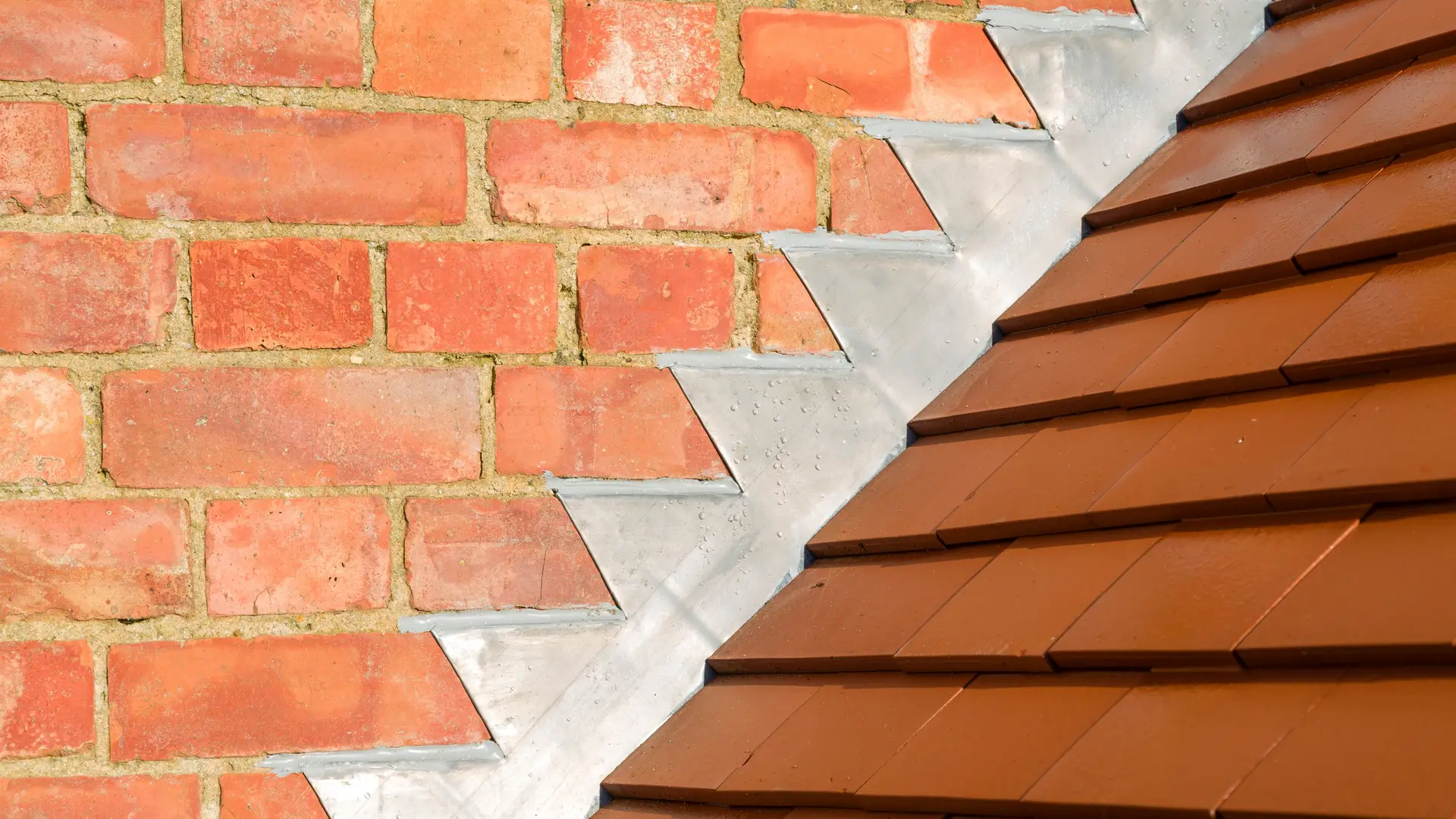 Lead step flashing where a tiled roof meets a brick wall