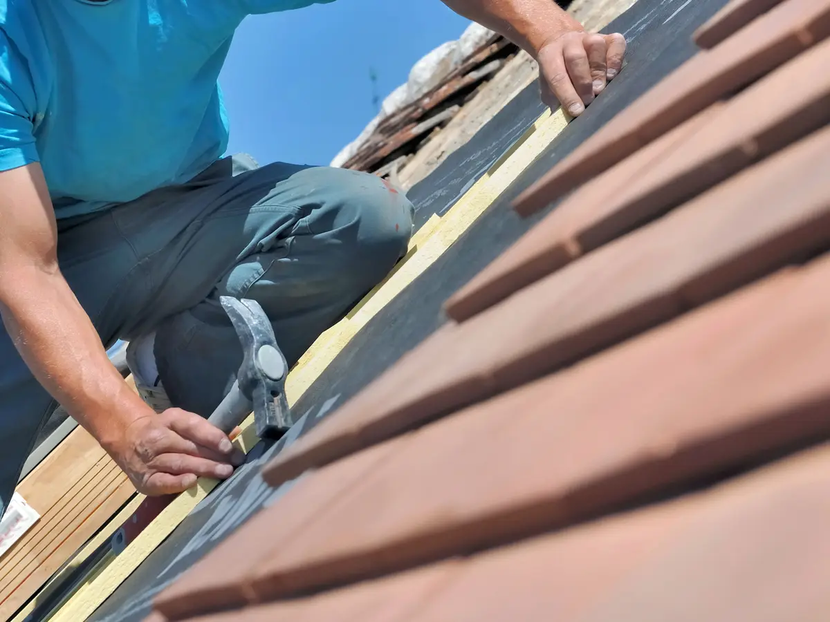 Roofer refixing clay tiles during a repair