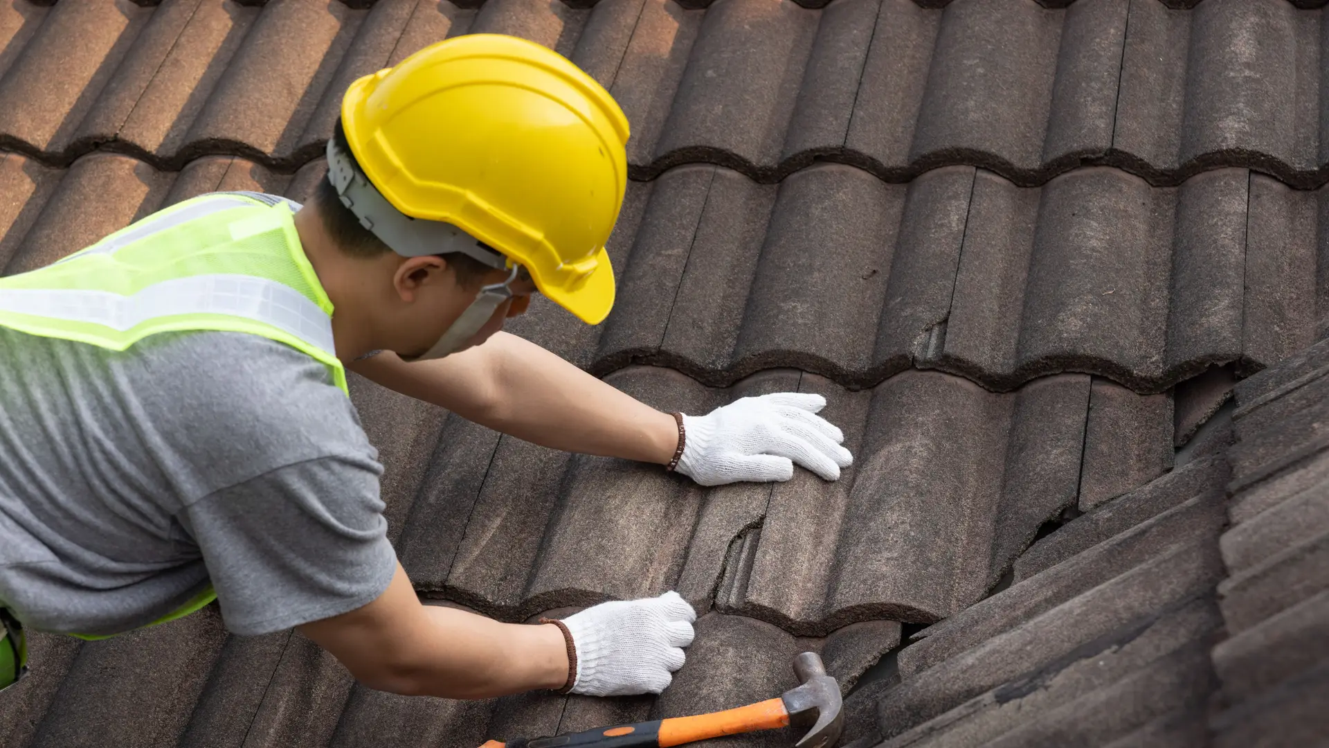 Roofer replacing a broken roof tile