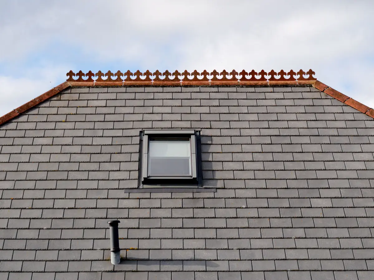 Grey slate roof with a roof window and clay ridge